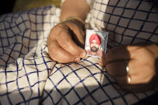 Kulwinder Kaur holds a photo of her husband, who abandoned her over 20 years ago to work in Italy, in the Indian state of Punjab on March 23, 2023. (Priyadarshini Ravichandran/The New York Times)