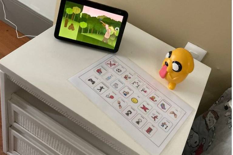 armário branco com tablet, tabela com desenho e boneco amarelo