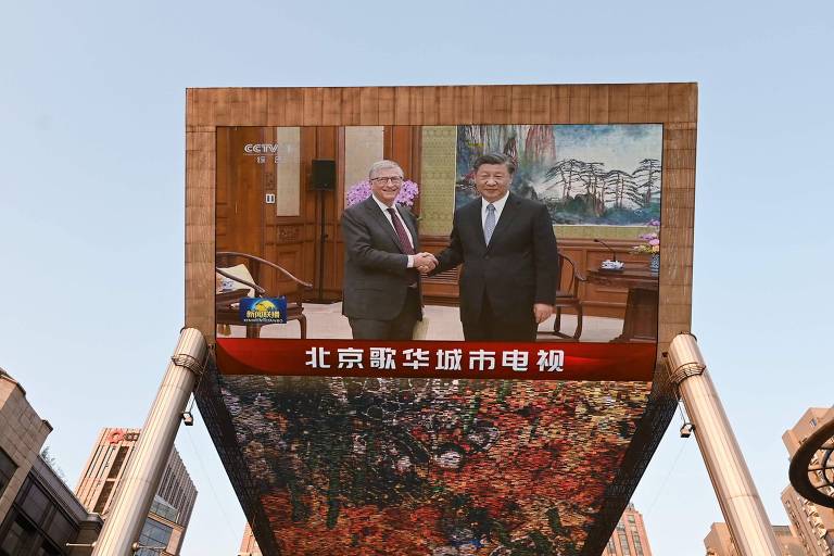 Na tela gigante de um shopping center em Pequim, uma transmissão da rede CCTV mostra o encontro do empresário Bill Gates com o líder chinês, Xi Jinping