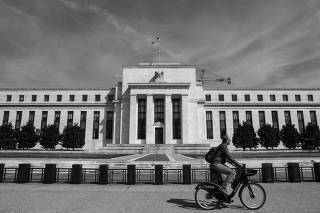 A man rides a bike in front of the Federal Reserve Board building on Constitution Avenue in Washington