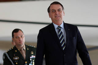 Brazil's President Jair Bolsonaro walks next army major, Mauro Cid before a meeting with Paraguay's President Mario Abdo (not pictured) at the Planalto Palace in Brasilia
