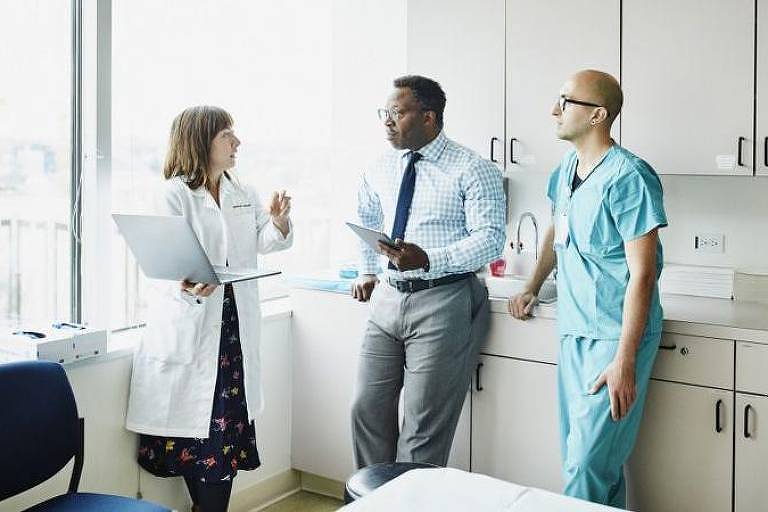 Três pessoas de equipe médica conversando em hospital