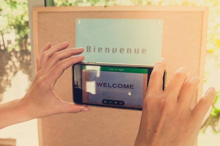 Pessoa apontando o celular para texto em francês, que na tela aparece traduzido para inglês
