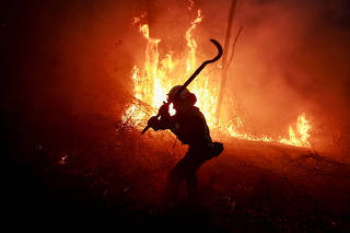 A Galician firefighter tackles flames in a forest during an outbreak of forest fires, in Peidrafita