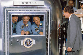 An undated photo provided by NASA shows, from left, Apollo 11 astronauts Neil Armstrong, Michael Collins and Buzz Aldrin Jr. as they speak to President Richard Nixon from the trailer in which they were quarantined after returning from the moon in July 1969. (NASA via The New York Times)