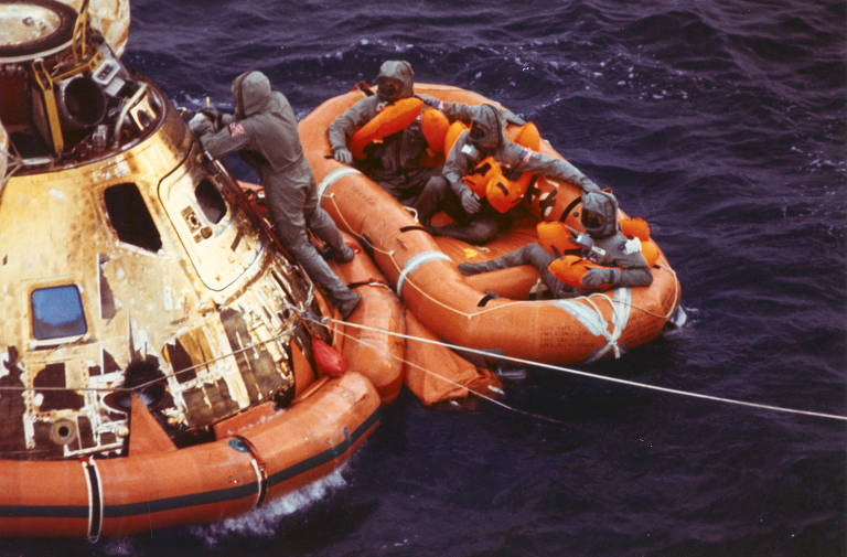 Fechamento da escotilha no módulo de comando da Apollo 11 enquanto os astronautas aguardam em uma balsa salva-vidas para serem resgatados por um helicóptero no oceano Pacífico, após a chegada da Lua, em 1969