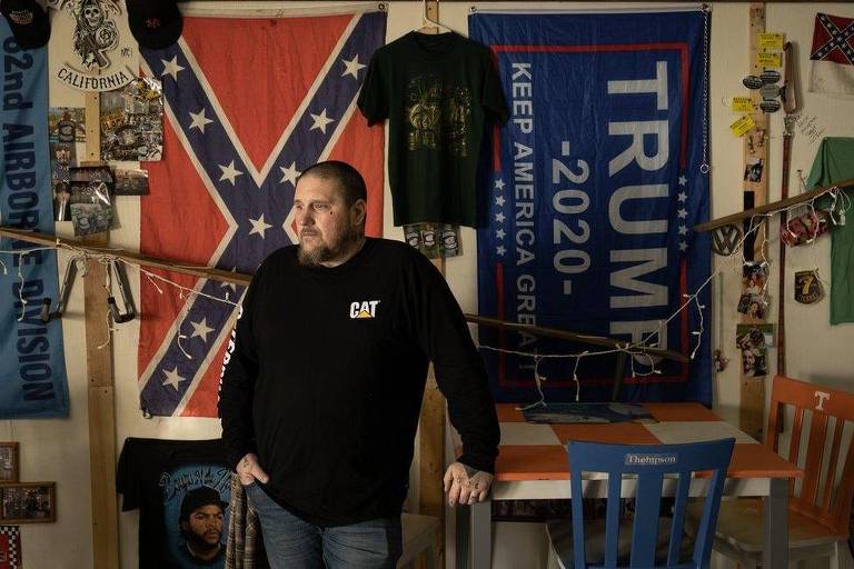 Homem em frente a bandeiras da confederação americana e de Trump