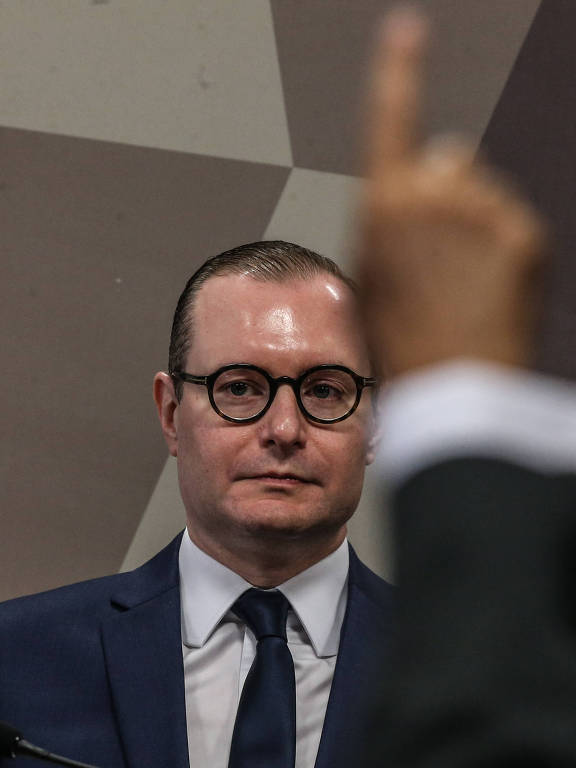 Cristiano Zanin durante sabatina no Senado para a vaga no STF; na foto, um dos senadores levanta o dedo para perguntar