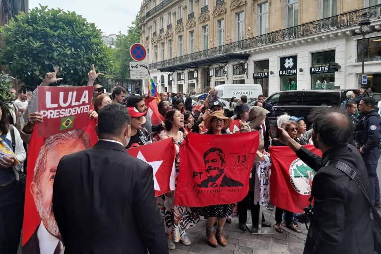 Grupo de pessoas segura bandeiras e faixas com o símbolo do PT e o rosto de Lula