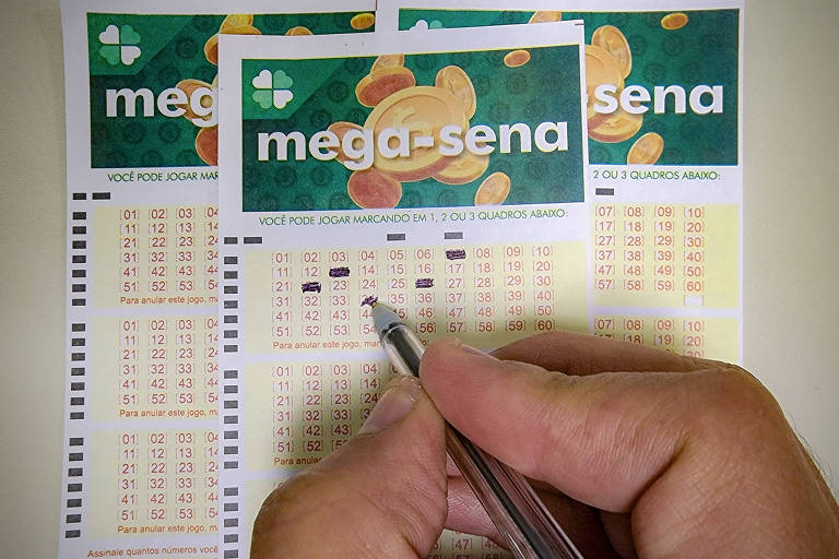 Mão marca números em um volante da mega-sena