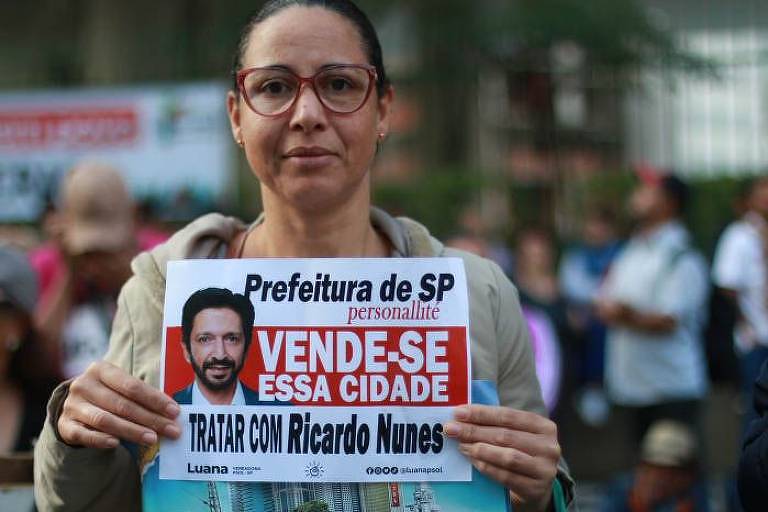 Manifestante com cartza em frente à Câmara Municipal