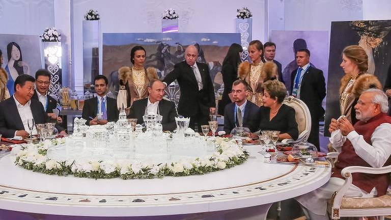 A então presidente Dilma Rousseff, de preto, durante encontro com Vladimir Putin em Moscou; atrás do líder russo está Ievguêni Prigojin; na mesa, respectivamente nos extremos esquerdo e direito da foto, estão o líder da China, Xi Jinping, e o premiê da Índia, Narendra Modi