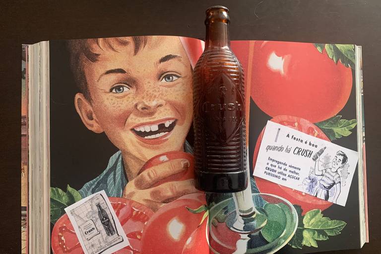 Material publicitário e uma antiga garrafa de Crush, de casco escuro e serrilhado