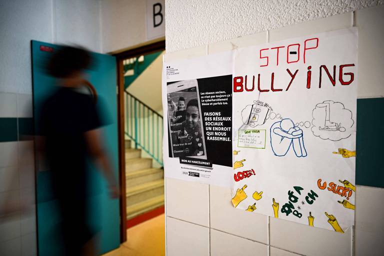 Estudante perto de cartaz com frase contra a prática do bullying em escola de Nogent-sur-Marne, na França