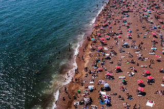 People enjoy the sun on the beach in Brighton