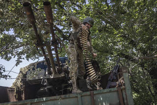 A Ukrainian marine with the 35th Brigade lifts ammunition from a truck bed along a tree line outside of Avdiivka, Ukraine, June 19, 2023. (David Guttenfelder/The New York Times)