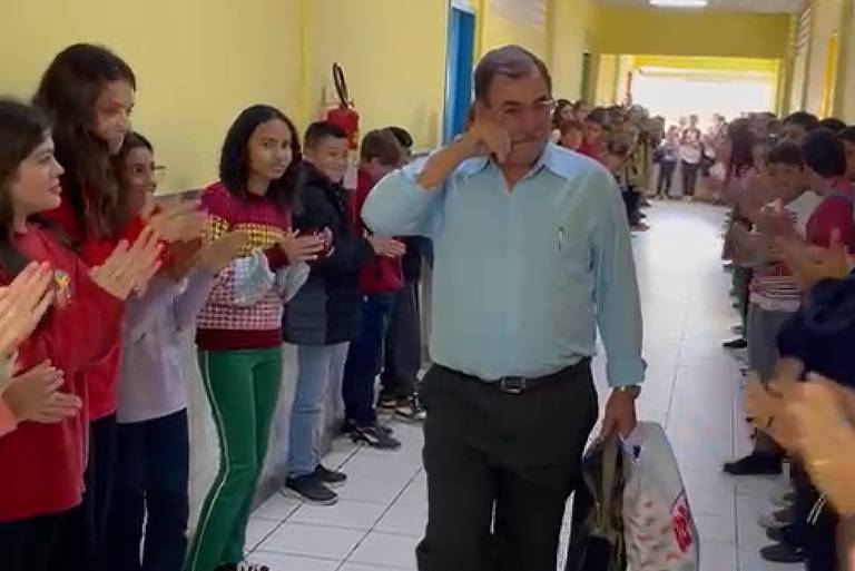 Homem chora enquanto é aplaudido em corredor por alunos