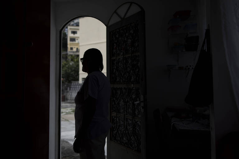 Imagem mostra a silhueta de uma mulher que foi resgatada de situação análoga à escravidão. Ela está em pé e não é possível identificá-la. Ao fundo, é possível ver uma porta, por onde passa a luz que gera a sombra da mulher.