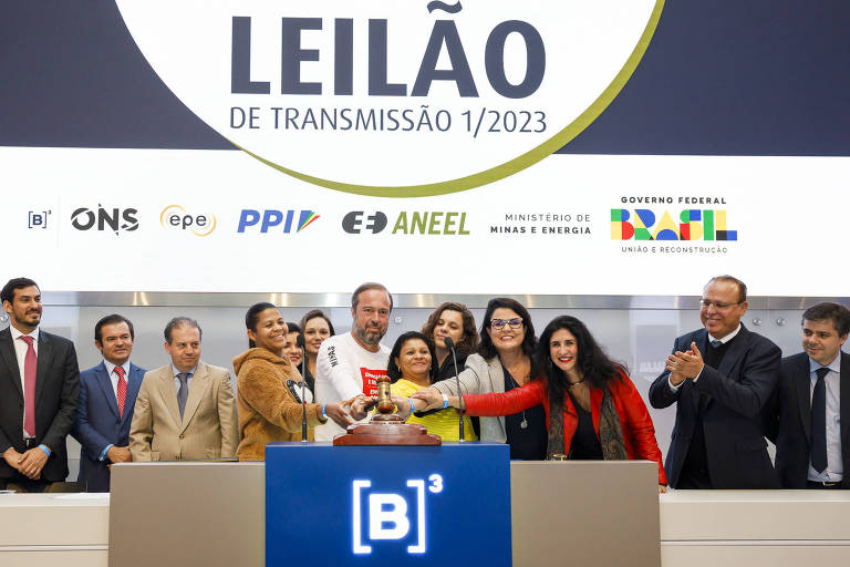 O ministro de Minas e Energia (ao centro, de branco), Alexandre Silveira, no primeiro leilão de linhas de transmissão de energia na sede da B3, em São Paulo; ele é um homem branco, de cabelo e barba grisalhos, usa uma camisa branca de manga comprida e está rodeado de mulheres e homens que seguram o martelo da B3