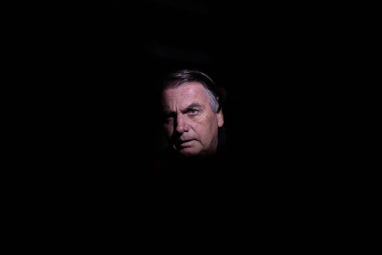 Ex-presidente Jair Bolsonaro em uma sala escura, na qual aparece apenas seu rosto