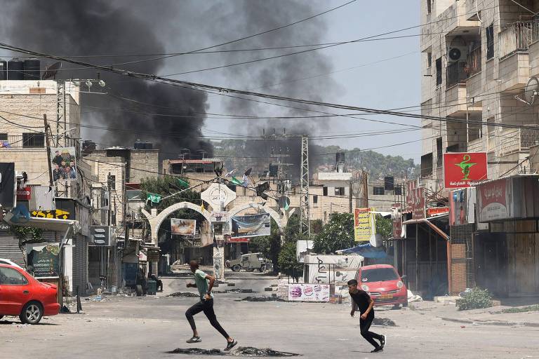 Palestinos correm durante ação militar israelense em Jenin, na Cisjordânia