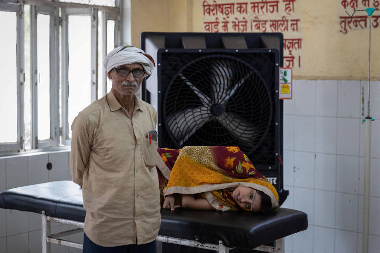 Reshmi Pathak, 30, que passou mal devido ao calor, aguarda atendimento ao lado do pai em ala de emergência de hospital no distrito de Ballia, no estado indiano de Uttar Pradesh