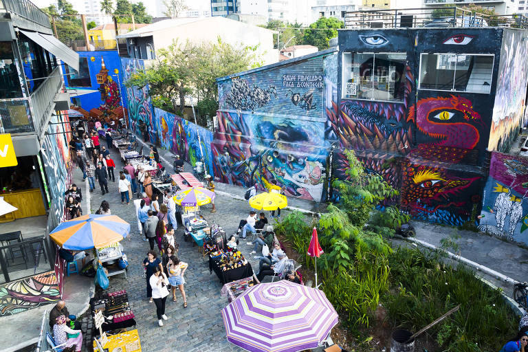 imagem aéreas de uma rua com uma praça e barracas vendendo artesanato com paredes dos prédios grafitadas