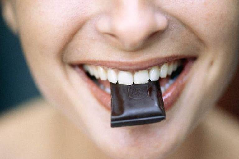 Mulher com pedaço de chocolate na boca