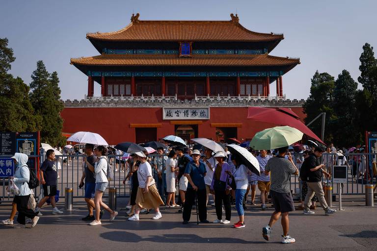 Pessoas com guarda-sol em frente a palácio em Pequim