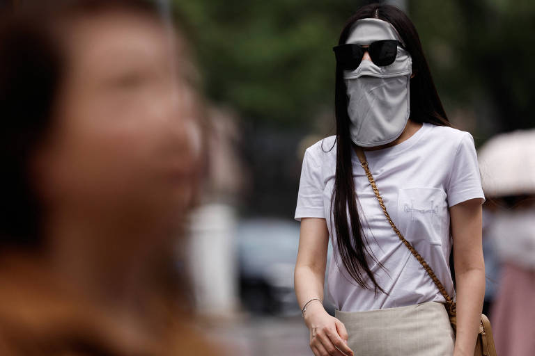 Mulher usa máscara facial de proteção solar em meio a onda de calor em Pequim, na China