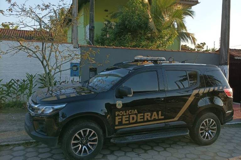 Carro da Polícia Federal estacionado em uma rua, em frente a uma casa