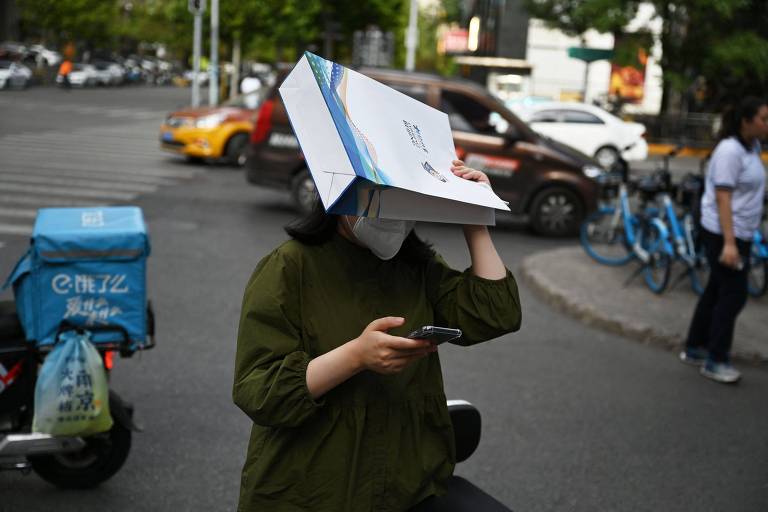 Mulher se protege do sol com sacola de papel na cabeça