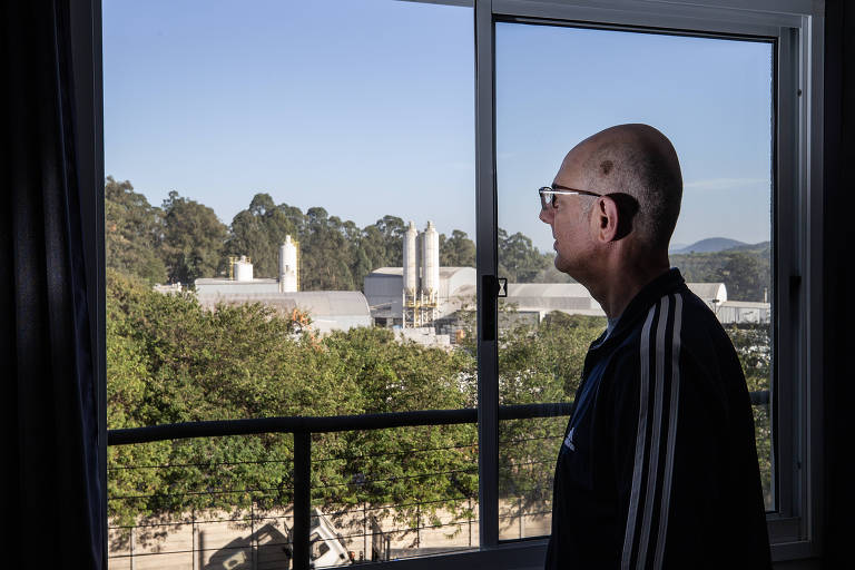 Carlos Alberto Bardini, 56, morador do Condomínio Certto Jaraguá, observa da sala do seu apartamento empresa de produção de concreto ligada à mineradora Riuma.