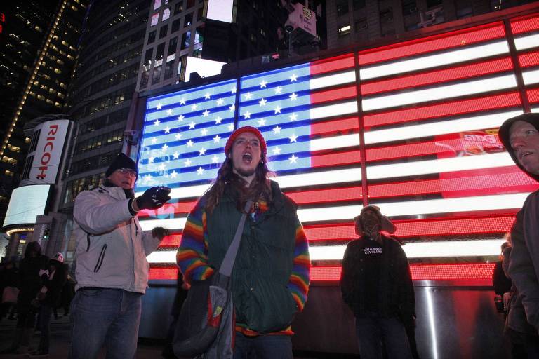 Manifestantes ligados ao "Ocupe Wall Street" durante protesto, com a imagem da bandeira dos Estados Unidos ao fundo, em Nova York.