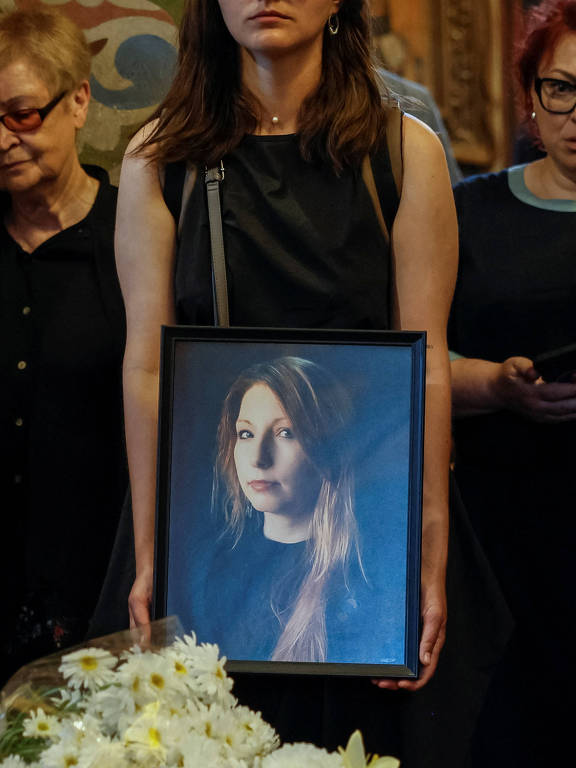 Uma amiga da escritora ucraniana Victoria Amelina, morta devido aos ferimentos provocados por um ataque russo, segura retrato da autora durante o funeral dela, em Kiev