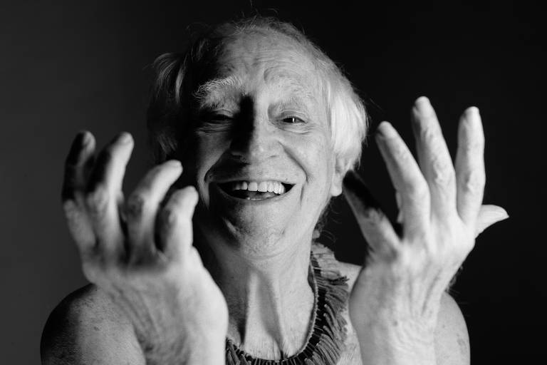 foto de zé celso em preto e branco, sorrindo, com as mãos diante do rosto