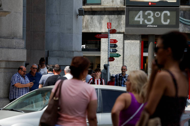 Pedestres em Bilbao, na Espanha, próximos de termômetro que registra 43º C
