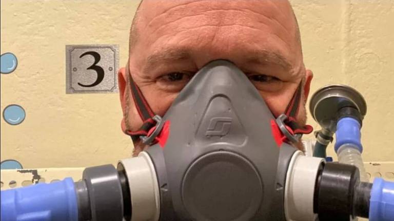 Homem com máscara de oxigênio cobrindo grande parte de seu rosto