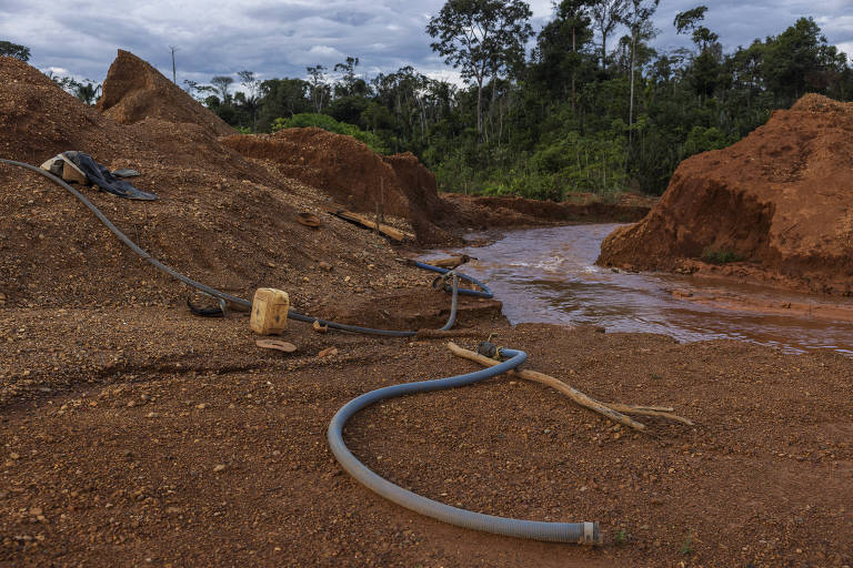 Máquinas e mangueiras em área de lama