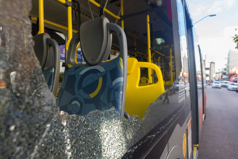 Imagem mostra uma grande janela do ônibus com o vidro quebrado 