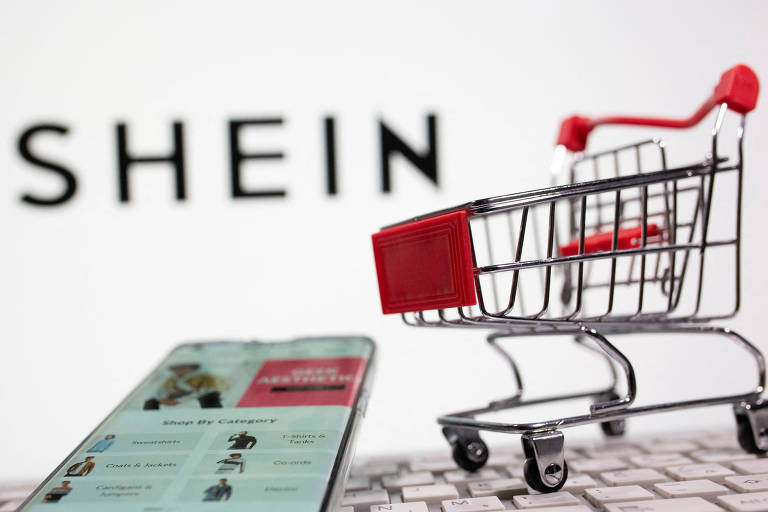 Imagem mostra um teclado e um carrinho de compras em miniatura em frente ao logo da Shein.