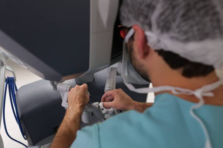 Por meio de joystick, médico controla "braços" do robô Da Vinci durante cirurgia.