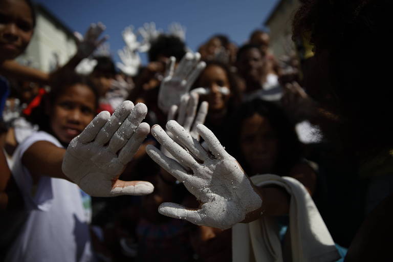 pessoas protestam exibindo palmas das mãos pintadas de branco