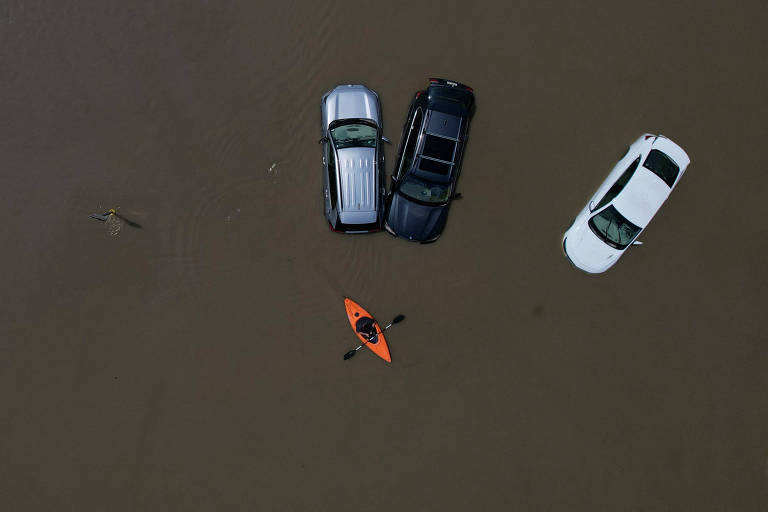 Morador em canoa passa perto de carros parcialmente submersos em água da chuva em Montpelier, no estado americano de Vermont