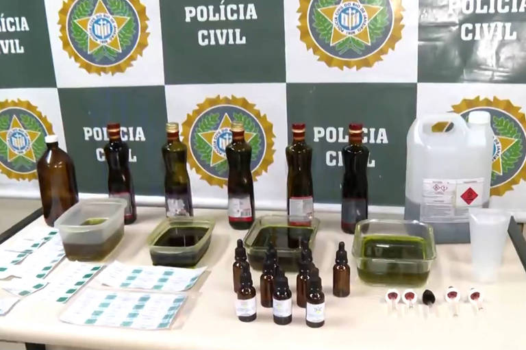 Na imagem, óleos de Cannabis e garrafas vazias em cima de mesa da polícia civil 