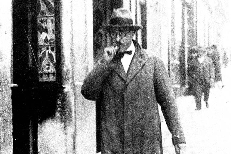 foto antiga de homem com bigodinho fumando na rua