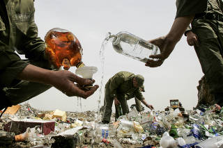 Security forces destroying seized alcohol bottles in Tehran, Iran. (The New York Times)