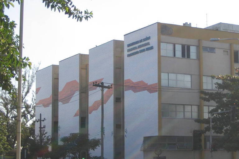 Quatro prédios brancos, com quatro andares, azulejos brancos e vermelhos. Placa com nome do hospital Francisco Silva Telles