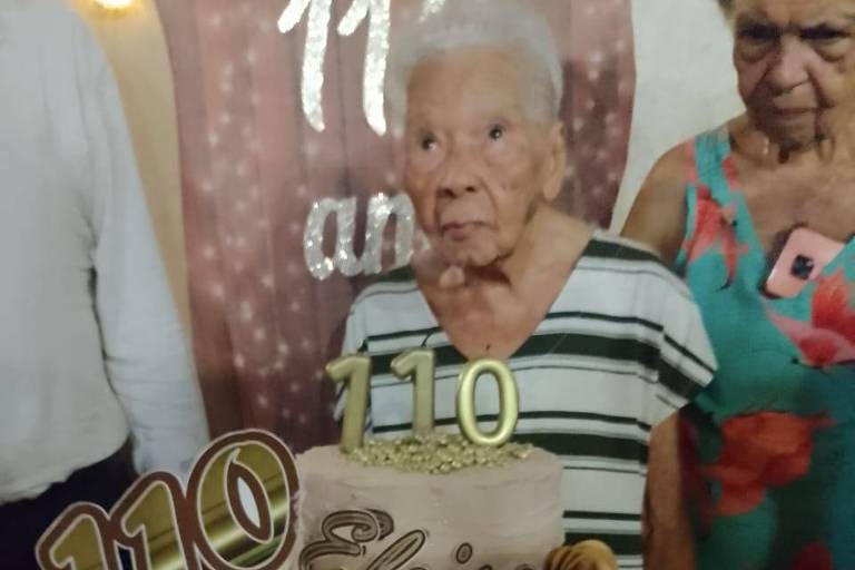 Idosa na frente de bolo com velas de 110 anos