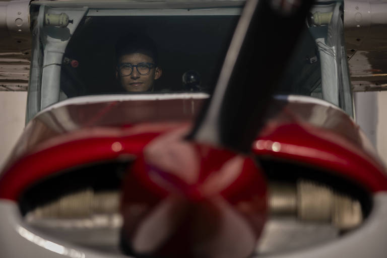 Imagem mostra homem na cabine de piloto de um avião de pequeno porte.